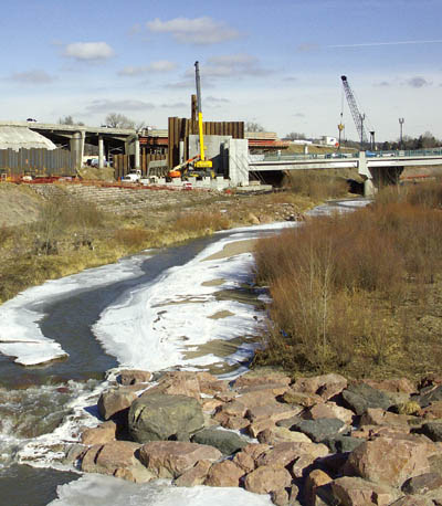 Bill Badger of Rockrimmon Constructors was asked to help
decipher this recent photo of COSMIX work (shot from the
Midland Trail footbridge over Monument Creek) at the
Colorado Avenue/I-25 bridges. His explanation is
summarized below: The white on the embankment at left is
plastic sheeting used for soil erosion. The vertical metal in
front of it, called sheet piling, has been driven into the
ground in case the embankment slips because the slope
there is known to be unstable. The bronze I-beams in the
middle have been driven into place to help support the
foundation for the northbound bridge, whose eastern side
will be 62 feet east of the current bridge. The yellow crane
is lifting concrete panels into place for the walls. Extending
down the middle of the avenue is what will be the bridges
center pier.
Westside Pioneer photo