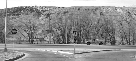 14th Street currently is only a right-in, right-out for
westbound Highway 24 traffic. To prevent the removal of
existing businesses at the intersection, a new interchange 
leading to collectors taking traffic to 21st and 8th streets 
and thus relieving the highway intersection at both those 
streets  could be situated back toward the erosion-scarred
slopes (background) of the Gold Hill Mesa property. 
Westside Pioneer photo