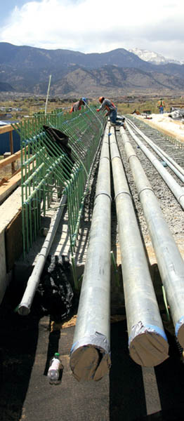 Beneath a vista of Pikes Peak, Cimarron bridge workers tidy
up recently laid rebar this week, while standing on conduits
for electrical and fiber lines that will run beneath the bridges sidewalk. 
Westside Pioneer photo