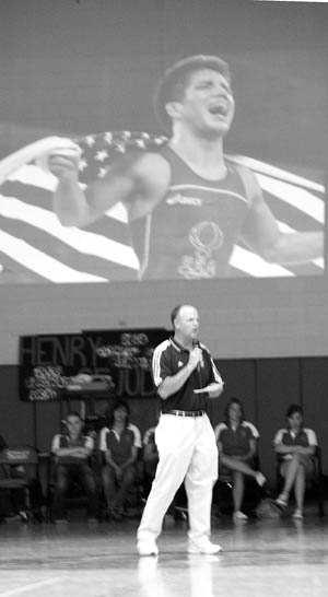 With an image from Henry Cejudos Olympic Games gold medal  celebration projected on the wall behind him, 
Coronado High wrestling coach Matt Brickell praises the athlete  whom he coached during the 2006 graduates two
years at the school  during an all-school assembly in the gymnasium Aug. 22. He chose to do the right thing and now hes golden, Brickell said.
Westside Pioneer photo