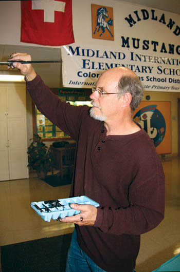 Fred Eyer puts finishing touches on his IB attitudes/profiles mural in the Midland Elementary lobby. He drew the globe 
and hands and created the caricatures for each attitude, while the profiles were clipped and positioned at the top. In the background, over his left shoulder, is part of 
his mural thats become the new Midland logo.
Westside Pioneer photo