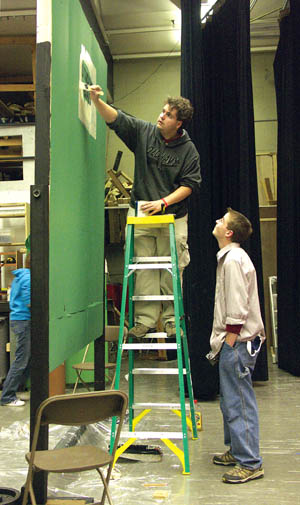 Devin Watts paints a set for the musical 'Grease' on the Coronado High stage while chatting with fellow student 
Evan Hooton this week. Plans call for the school's new auditorium to have a separate room for set preparation so the work will not have to be done on the stage 
anymore.
Westside Pioneer photo
